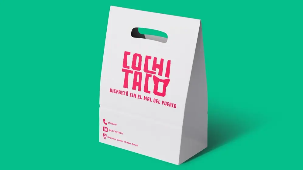 White paper bag with a die-cut handle, pink Cochitaco logo and contact details at the bottom, on a green background