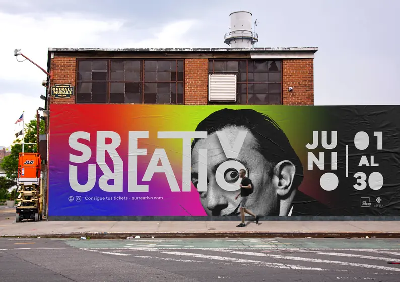 Large Surreativo wall poster on a street, with a black and white portrait, the June dates and a pedestrian walking by