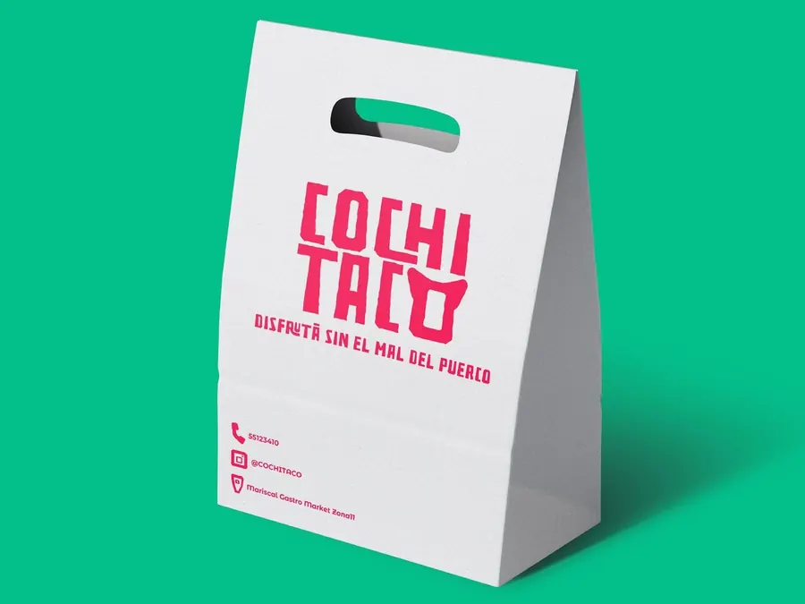 Takeout paper bag with the pink Cochitaco logo and tagline on a green background, by CBAS