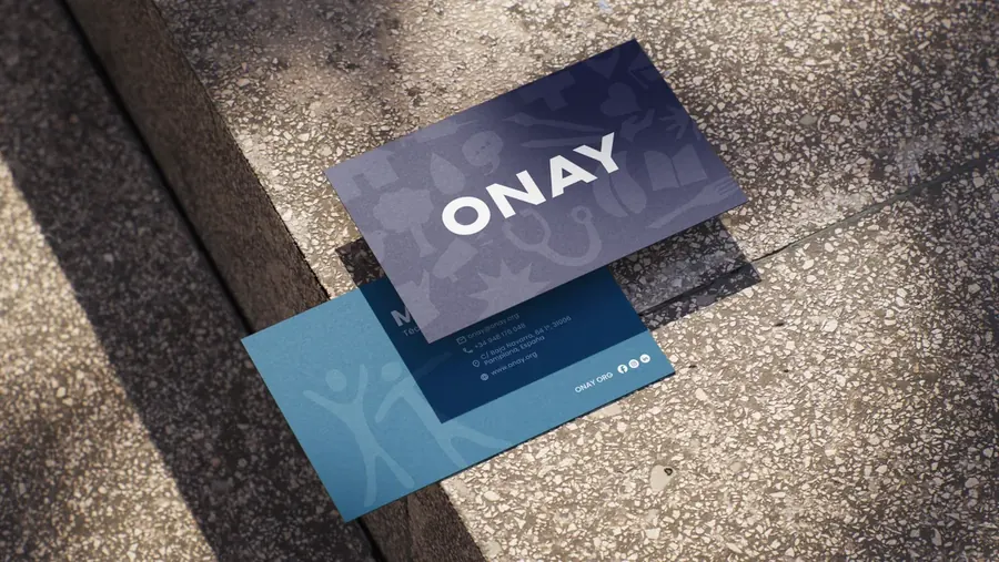 Tarjetas de presentación de ONAY en azul marino y azul claro sobre un escalón de piedra